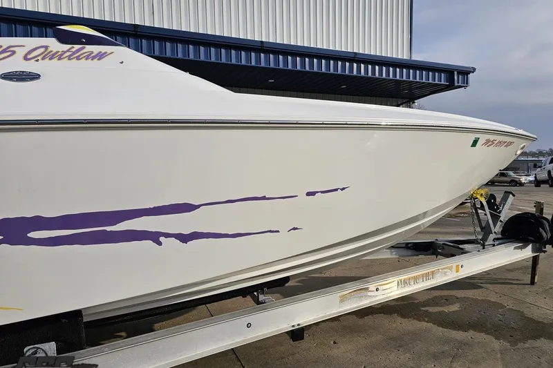 Slide: The Image of 2003 Baja 25 Outlaw boat on trailer with purple graphics, parked outdoors. - 6