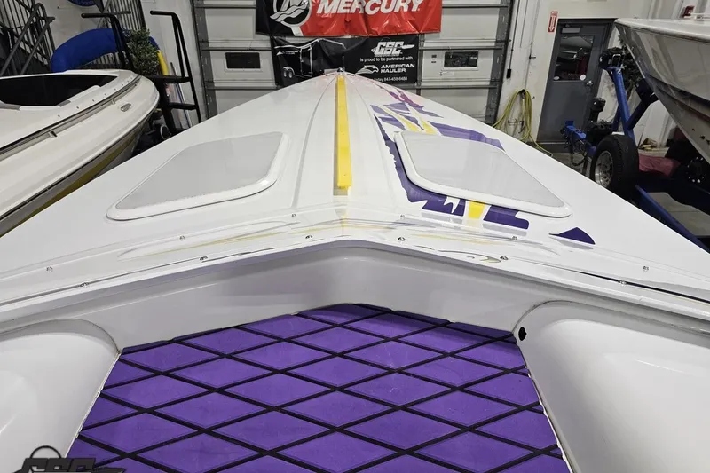Slide: The Image of 2003 Baja 25 Outlaw boat with vibrant purple and yellow design in a garage setting. - 64