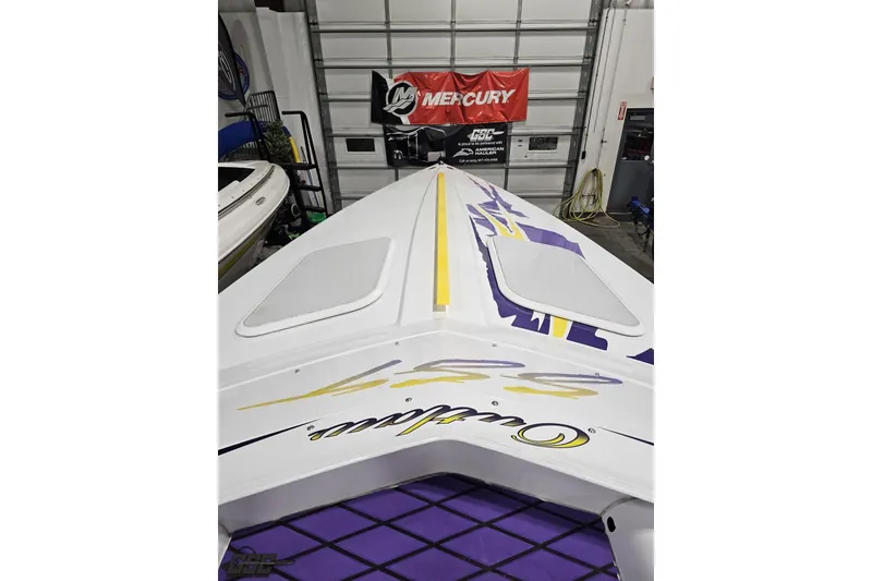 Slide: The Image of 2003 Baja 25 Outlaw boat with vibrant graphics in a garage setting. - 65