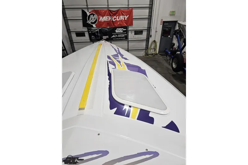 Slide: The Image of 2003 Baja 25 Outlaw boat with vibrant graphics in a garage setting. - 66