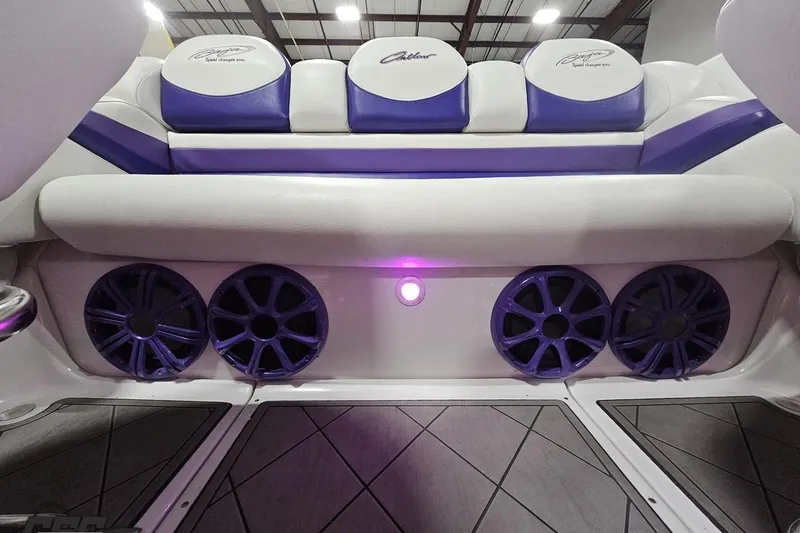 Slide: The Image of 2003 Baja 25 Outlaw boat interior with purple and white seating, featuring four speakers. - 71