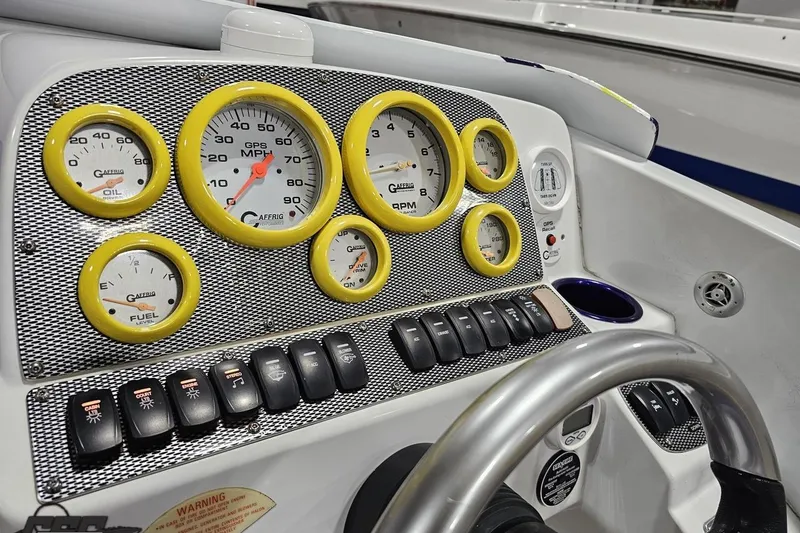 Slide: The Image of Dashboard of a 2003 Baja 25 Outlaw boat with yellow-rimmed gauges and control switches. - 73