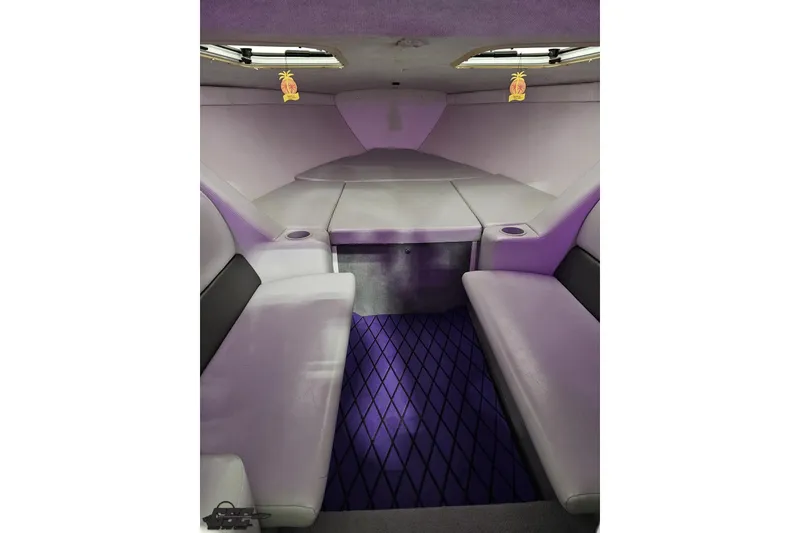 Slide: The Image of Interior of 2003 Baja 25 Outlaw boat with purple seating and ambient lighting. - 78