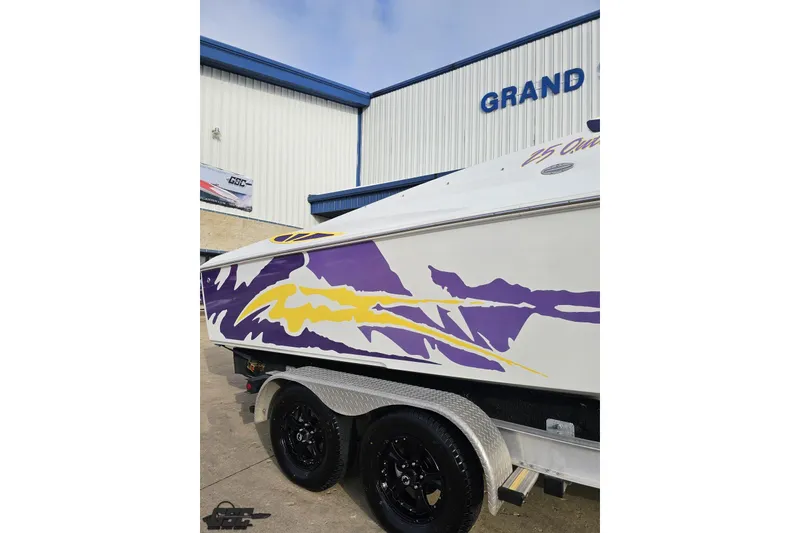Slide: The Image of 2003 Baja 25 Outlaw boat with vibrant purple and yellow graphics on trailer. - 8