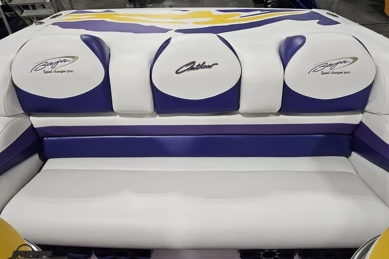 Slide: The Image of 2003 Baja 25 Outlaw boat interior with white and purple seating, featuring branded logos. - 88