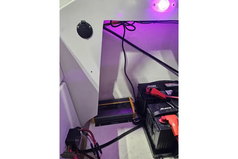 Slide: The Image of 2003 Baja 25 Outlaw boat interior with batteries and wiring under purple lighting. - 98