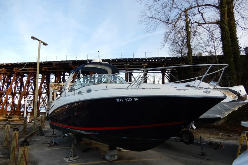 The Image of 2004 Sea Ray 300 Sundancer boat on dry dock near a wooden bridge. - 0