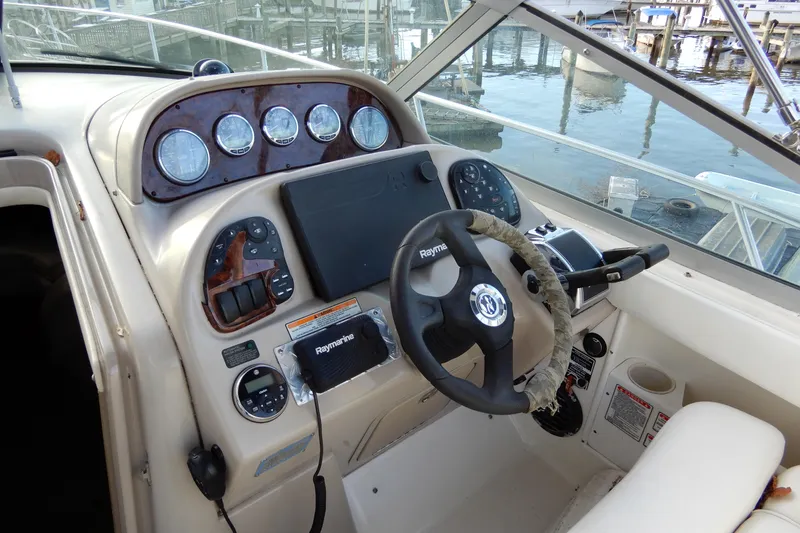 Slide: The Image of 2004 Sea Ray 300 Sundancer helm with steering wheel and navigation instruments. - 13