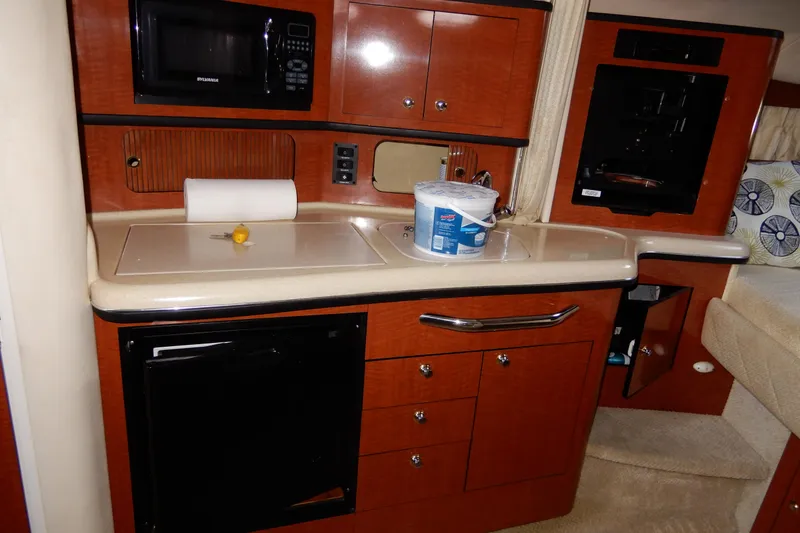 Slide: The Image of 2004 Sea Ray 300 Sundancer kitchen with microwave, sink, and storage cabinets. - 5