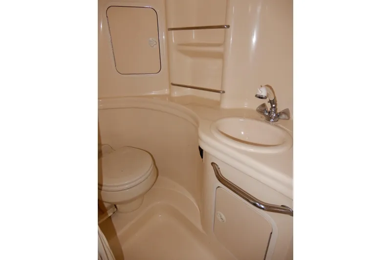 Slide: The Image of 2004 Sea Ray 300 Sundancer bathroom with sink, toilet, and storage shelves. - 8