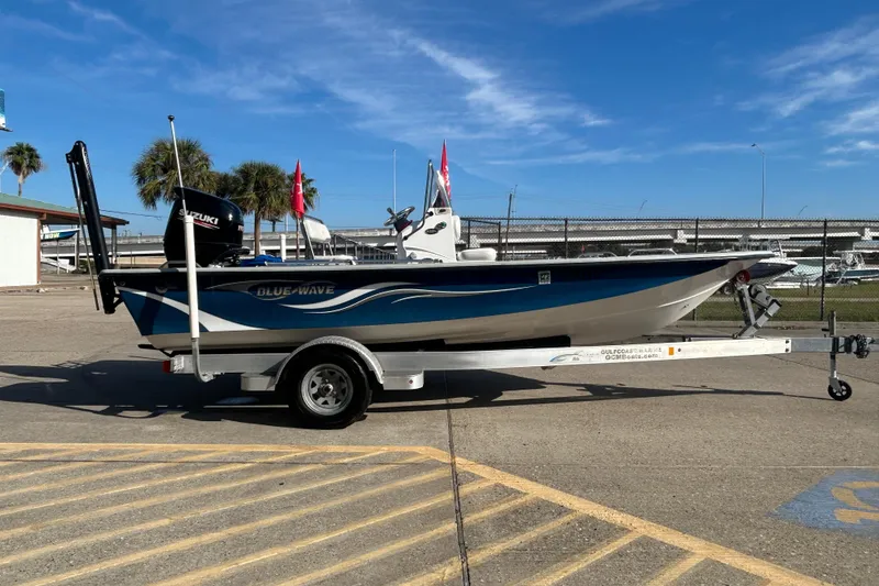 Slide: The Image of 2017 Blue Wave 1900 STL boat on trailer, parked outdoors under clear blue sky. - 4