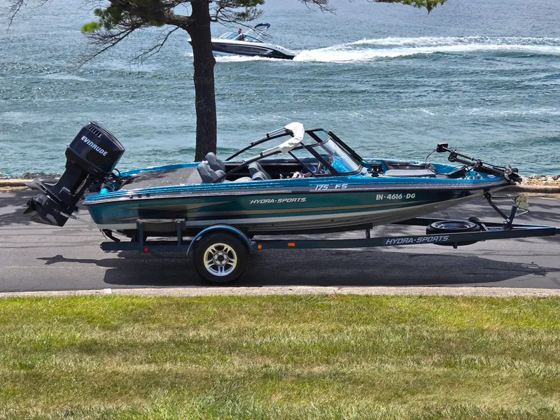 The Image of 1994 Hydra-Sports 175 FS boat on trailer by a lake, with Evinrude motor. - 0