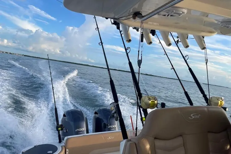 Slide: The Image of 2019 Scout 275 LXF boat with fishing rods and twin engines on open water. - 2