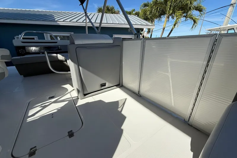 Slide: The Image of 2023 Hurricane FunDeck 2260 RE OB interior with seating and storage, under clear blue sky. - 18
