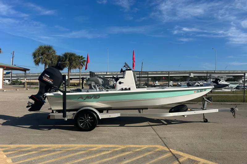 Slide: The Image of 2024 Avid 21 FS boat on trailer, parked outdoors under clear blue sky. - 4