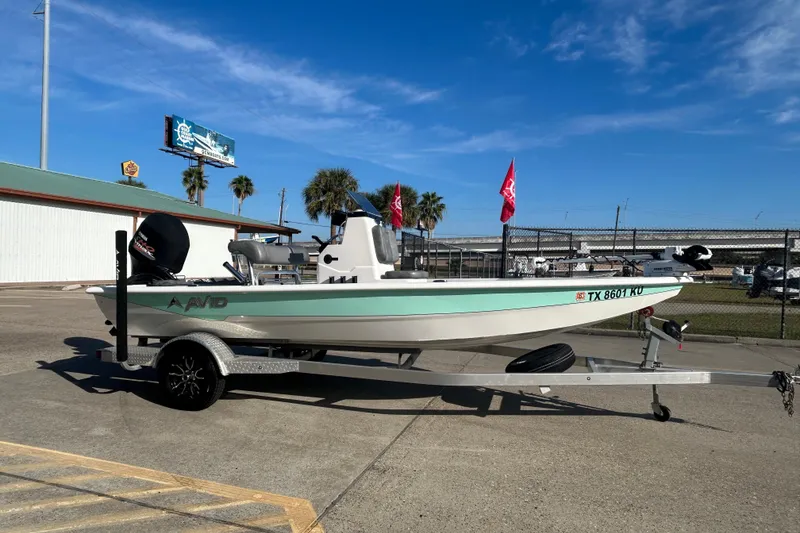 Slide: The Image of 2024 Avid 21 FS boat on trailer, parked outdoors under clear blue sky. - 8