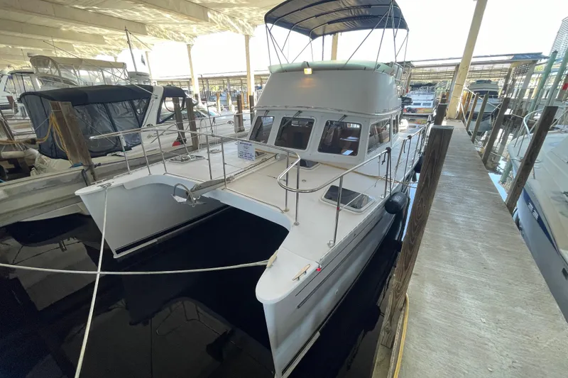 Slide: The Image of 2006 PDQ 34 Power Catamaran docked in a marina under a covered slip. - 2