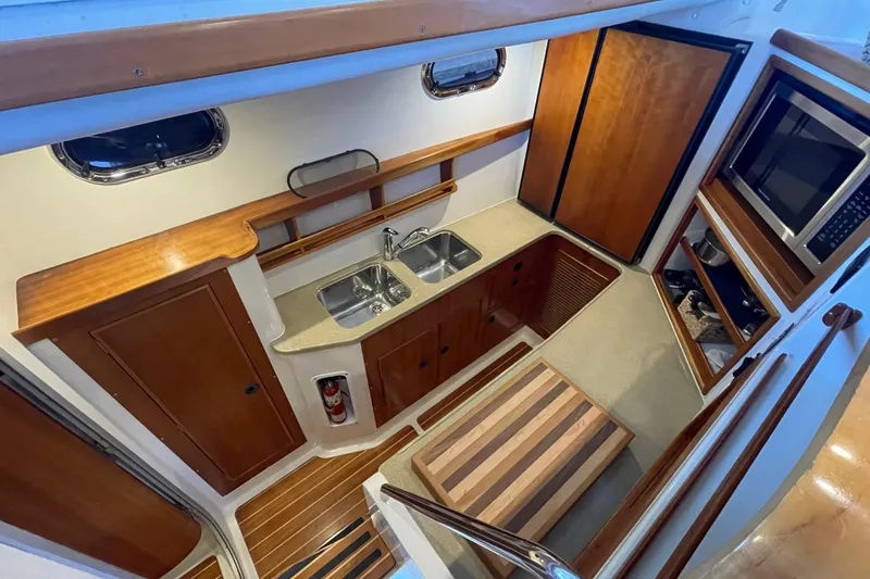 Slide: The Image of Interior of 2006 PDQ 34 Power Catamaran, featuring a compact kitchen with wood accents. - 28