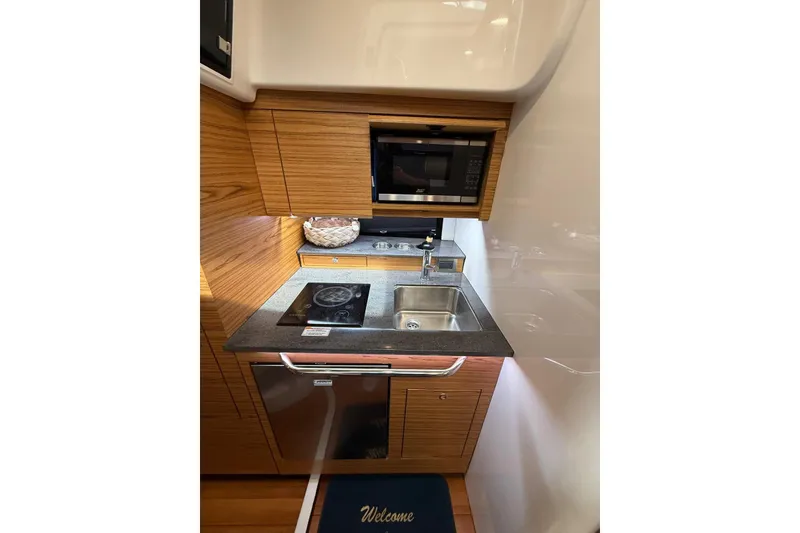 Slide: The Image of 2024 Boston Whaler 405 Conquest kitchen with stove, sink, and microwave. - 6