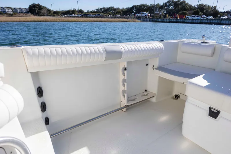 Slide: The Image of 2006 Sailfish 2660 WAC boat interior with white seating and storage, docked by the water. - 17