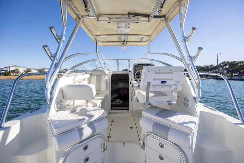 Slide: The Image of 2006 Sailfish 2660 WAC boat interior with seating and helm, on calm water. - 19