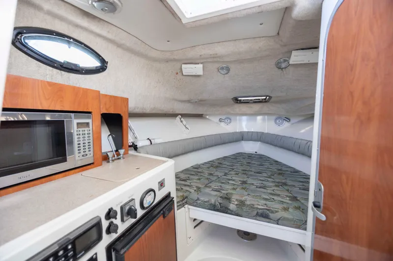Slide: The Image of 2006 Sailfish 2660 WAC cabin interior with bed, microwave, and compact kitchen area. - 30