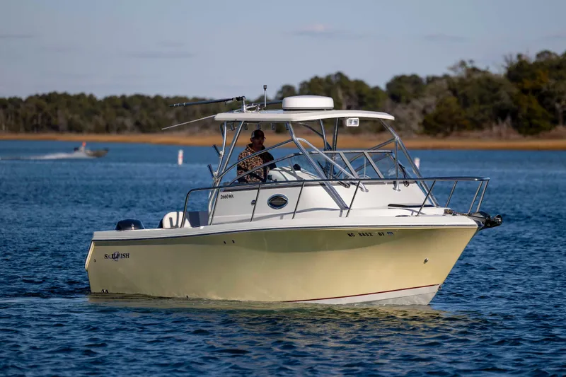 Slide: The Image of 2006 Sailfish 2660 WAC boat cruising on a calm lake with trees in the background. - 6