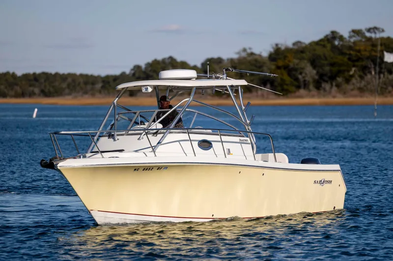 Slide: The Image of 2006 Sailfish 2660 WAC boat cruising on a serene lake with forested background. - 8