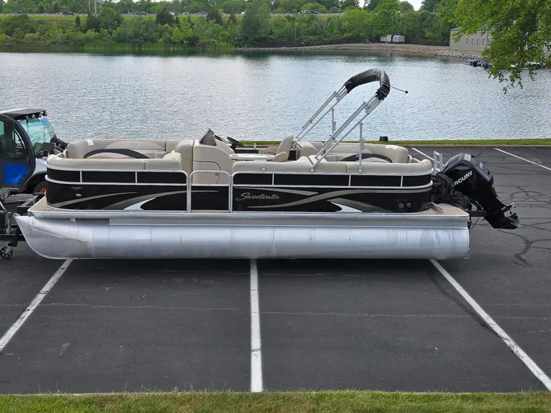 The Image of 2012 Sweetwater 2486 pontoon boat parked near a scenic lake. - 0
