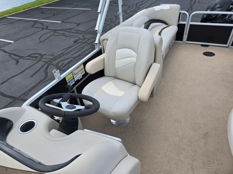 Slide: The Image of 2012 Sweetwater 2486 boat interior with beige seating and steering wheel. - 14
