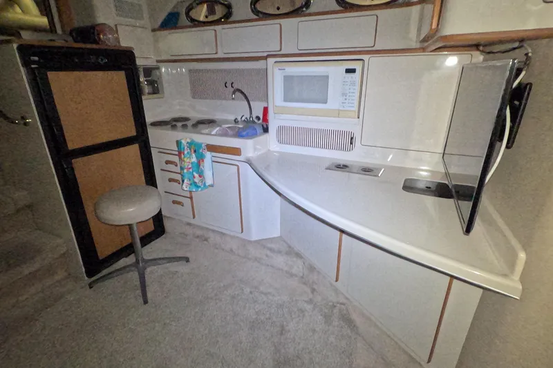 Slide: The Image of 1995 Sea Ray 400 Express Cruiser kitchen with microwave, stove, and seating. - 25