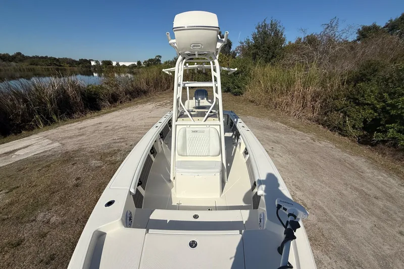 Slide: The Image of 2025 Pathfinder 2400 Open boat on a lakeside dirt path, clear sky background. - 24