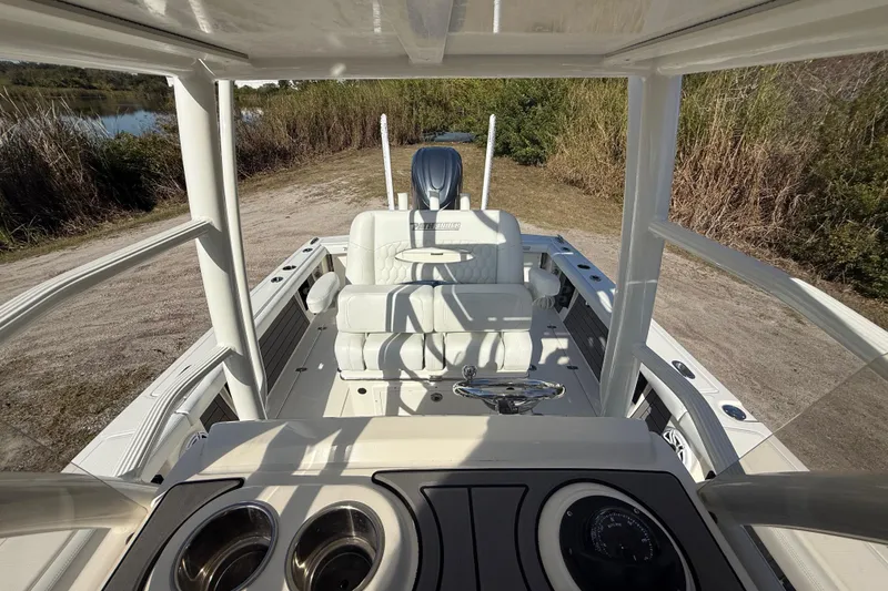 Slide: The Image of 2025 Pathfinder 2400 Open boat interior with seating and console, docked near a grassy shoreline. - 26