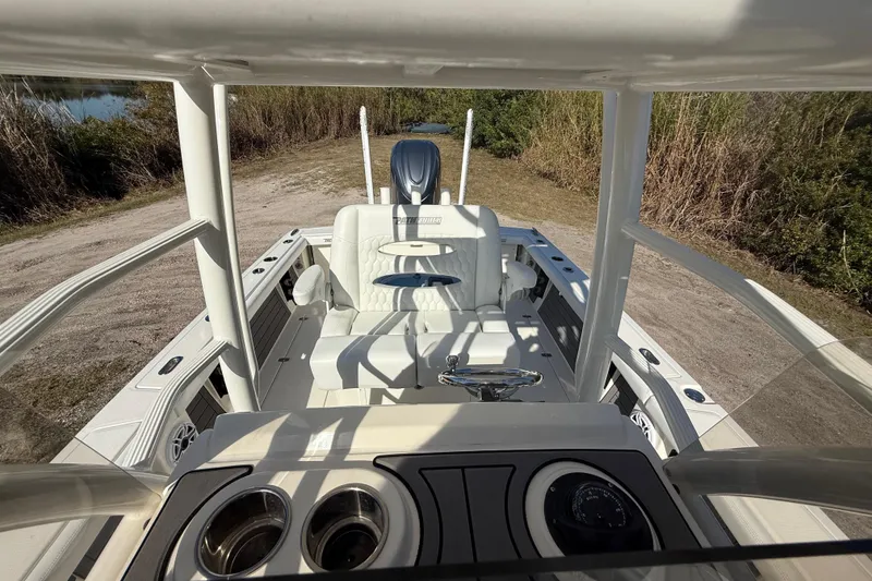 Slide: The Image of 2025 Pathfinder 2400 Open boat interior with steering console and seating, parked on a dirt path. - 27