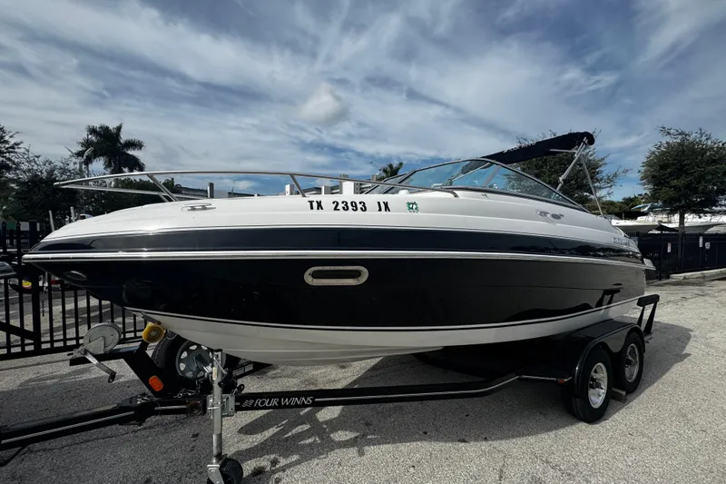 Slide: The Image of 2004 Four Winns 205 Sundowner boat on trailer, parked outdoors under cloudy sky. - 2