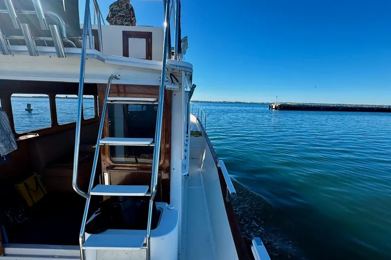 Slide: The Image of 1979 Californian 34 boat on calm water, featuring a ladder and cabin view. - 20