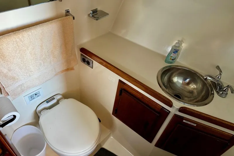 Slide: The Image of Compact bathroom in a 1979 Californian 34 boat, featuring a sink, toilet, and towel rack. - 31