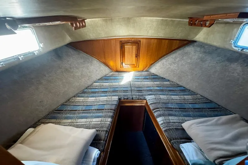 Slide: The Image of Cozy cabin interior of a 1979 Californian 34 boat with plaid bedding and wooden accents. - 36