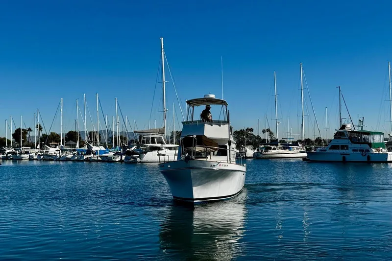 Slide: The Image of 1979 Californian 34 boat navigating marina with sailboats in background under clear blue sky. - 4