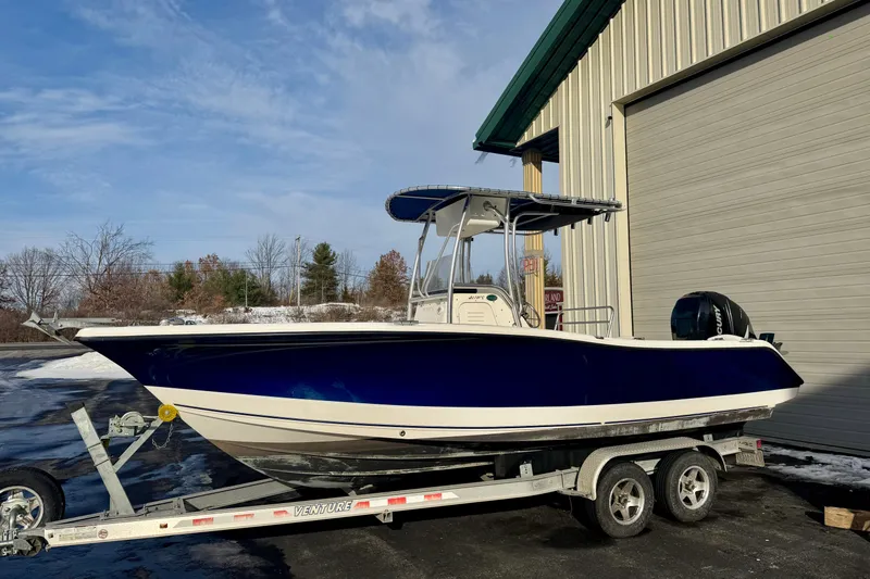 Slide: The Image of 2010 Trophy 2203 Center Console boat on trailer, parked outside a building. - 1