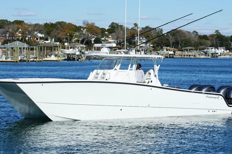 Slide: The Image of 2024 Freeman 38 boat cruising on a serene blue lake with scenic background. - 10