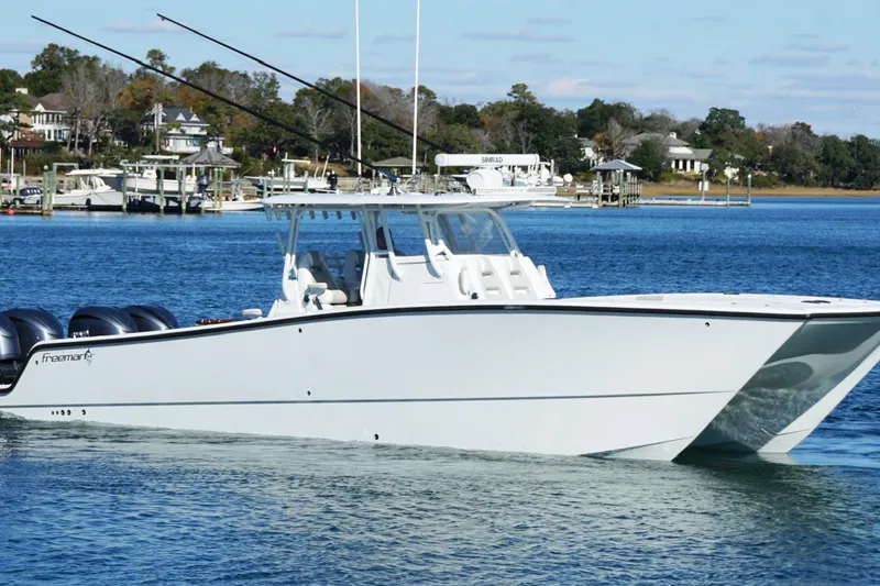 Slide: The Image of 2024 Freeman 38 boat cruising on a serene lake with a scenic background. - 13