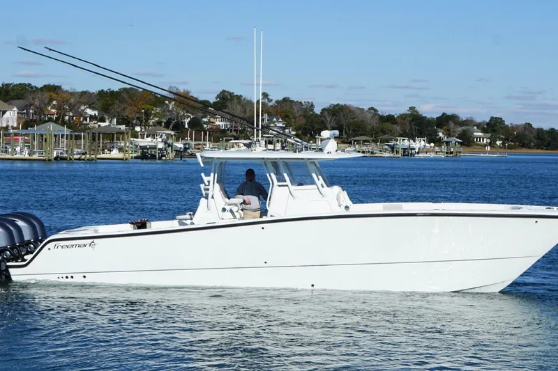 Slide: The Image of 2024 Freeman 38 boat cruising on a calm lake with scenic shoreline background. - 14