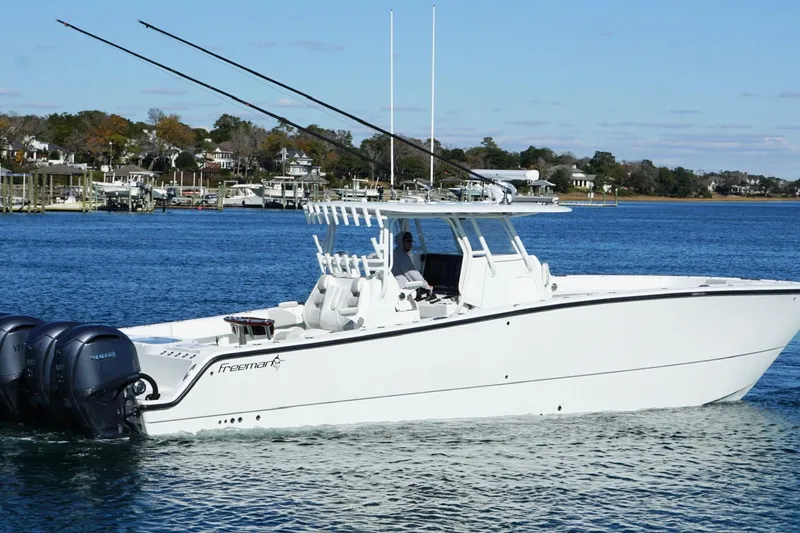 Slide: The Image of 2024 Freeman 38 boat cruising on a calm blue lake with scenic shoreline. - 3