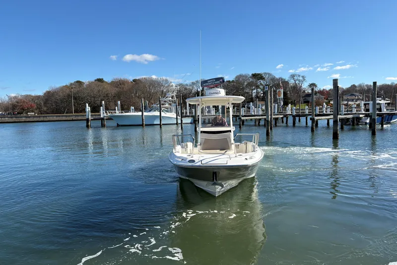 Slide: The Image of 2018 Boston Whaler 270 Dauntless boat navigating a marina under clear blue skies. - 12