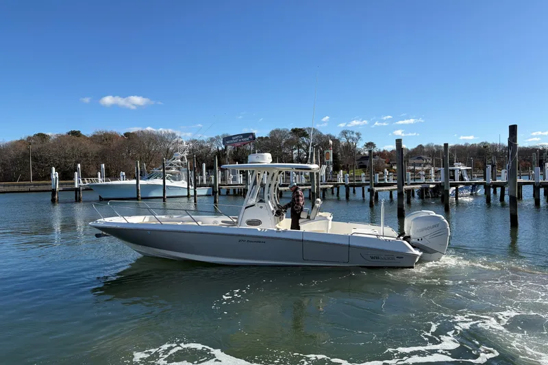 Slide: The Image of 2018 Boston Whaler 270 Dauntless boat cruising in a marina under clear blue skies. - 17