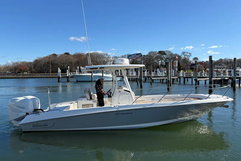 Slide: The Image of 2018 Boston Whaler 270 Dauntless boat on calm water near a marina. - 18