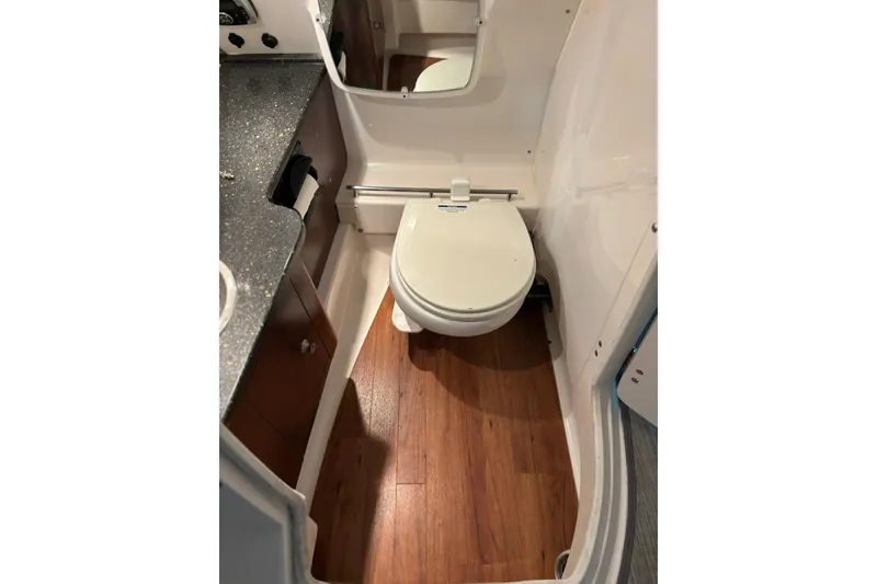 Slide: The Image of 2016 Chaparral 287 SSX boat bathroom with wood flooring and compact toilet. - 16