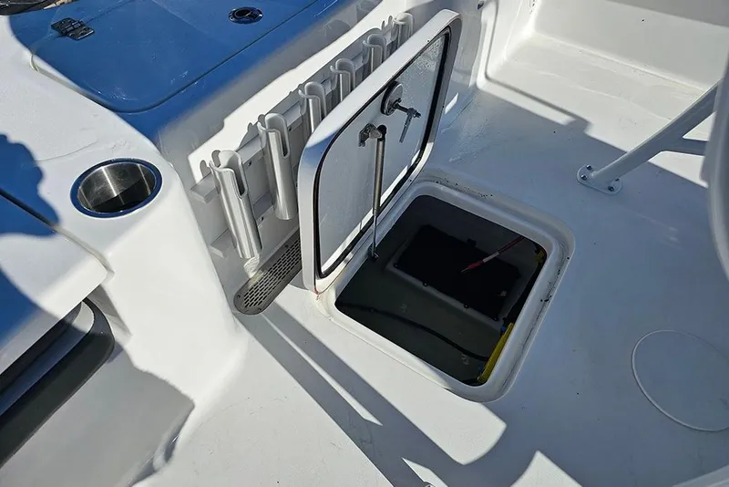 Slide: The Image of 2026 Sea Pro 210 Bay boat interior with open storage compartment and rod holders. - 17