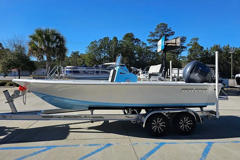 Slide: The Image of 2026 Sea Pro 210 Bay boat on trailer, parked outdoors under clear blue sky. - 6